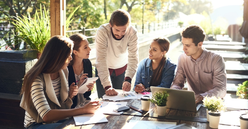 Group of professional men and women sitting around a table having a lighthearted discussion.
